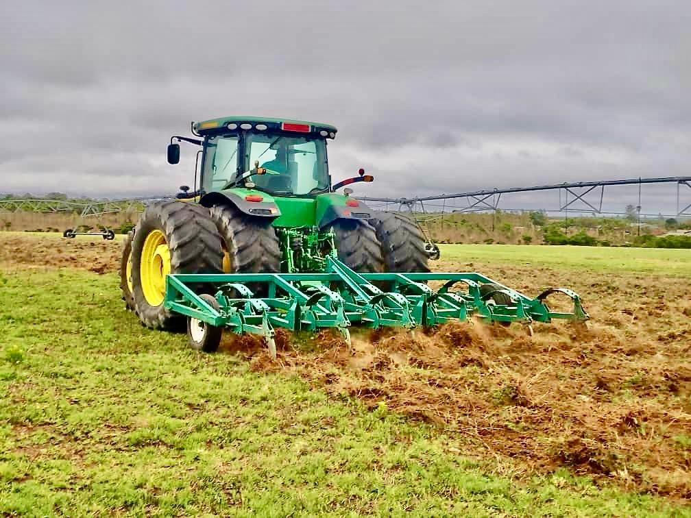 Riptill John Deere tractor pulling a ripper across irrigated pasture in Zimbabwe