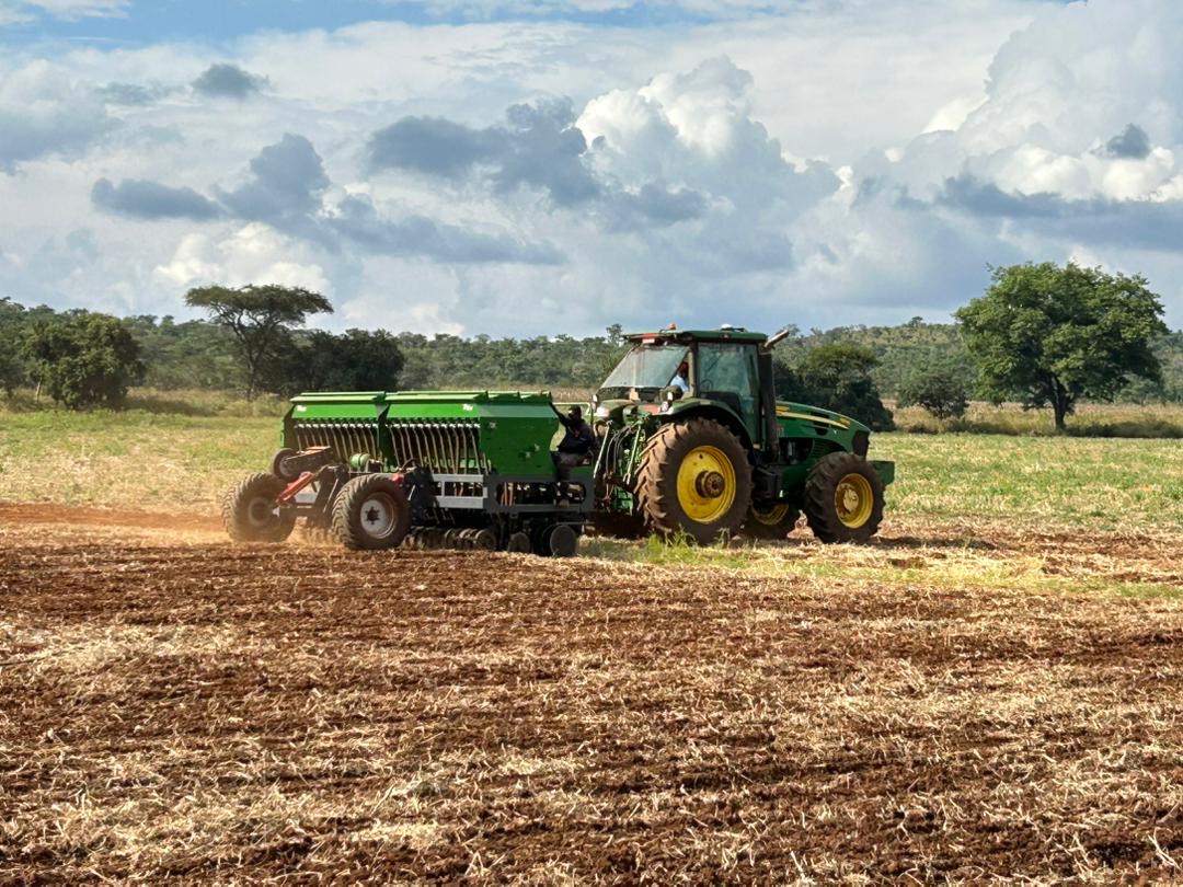 John Deere tractor sowing with a seed drill across stubble field