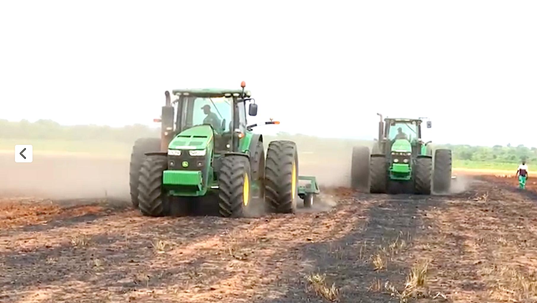 Two Riptill John Deere tractors discing a field in a cloud of dust in Zimbabwe