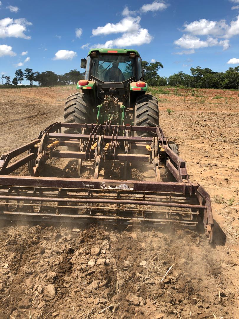 Rear view of a John Deere tractor pulling a chisel plough on newly cleared land