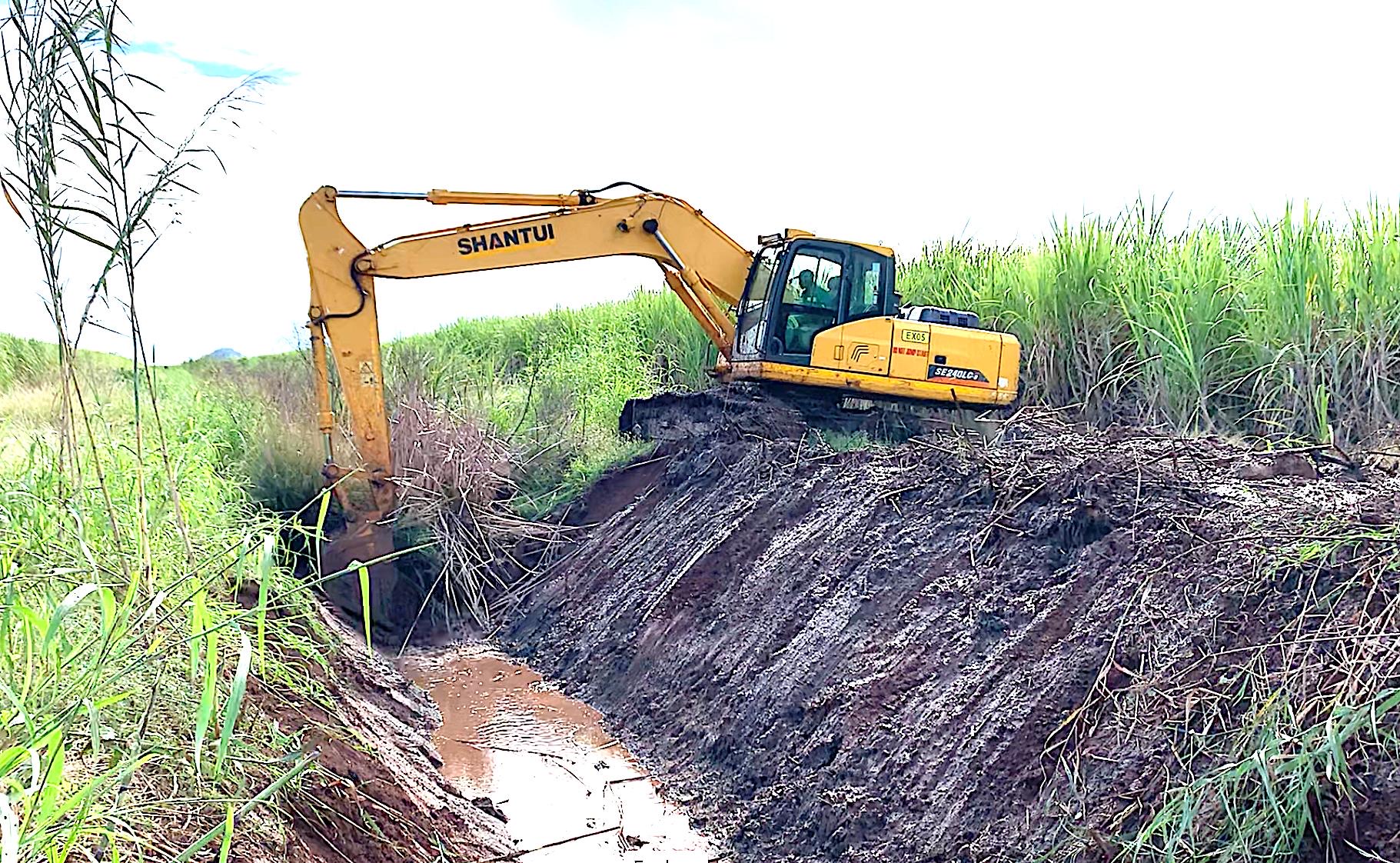 Shantui SE240 excavator cutting a drain alongside a cane field